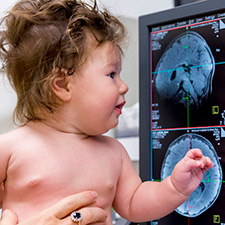 baby in front of mri scans on screen
